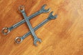 Three iron chrome wrenches lie in a heap on a wooden background