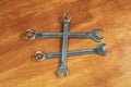 Three iron spanners crossed, builder`s hand tool lies on a wooden background Royalty Free Stock Photo