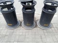 three iron trash cans in a black city park