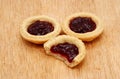 Three jam tarts, one with a bite taken, on a wooden table Royalty Free Stock Photo
