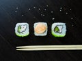 Three Japanese rolls at an angle, light chopsticks and sprinkled sesame seeds Royalty Free Stock Photo