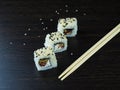 Three Japanese rolls at an angle, light chopsticks
