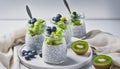Three jars of chia seed pudding, topped with fresh kiwi slices and blueberries, beside a halved coconut and kiwi on a white