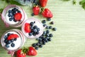 Three jars of yogurt with blueberries and strawberries, square.