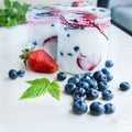 Three jars of yogurt with blueberries and strawberries, square.