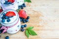 Three jars of yogurt with blueberries and strawberries, square.