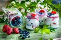 Three jars of yogurt with blueberries and strawberries, square.