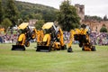 Three JCB Backhoe loaders with vehicle passing underneath them, dancing diggers Royalty Free Stock Photo