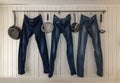 Three jeans hanging on a kitchen rail to dry