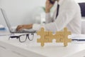 Three joined jigsaw puzzle pieces on desk against blurred office room with man working on laptop Royalty Free Stock Photo