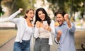 Three Joyful Friends With Cellphone Shaking Fists Celebrating Victory Outdoor Royalty Free Stock Photo
