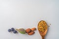 Three juniper blue old berries, almonds nut and bee pollen in wooden spoon on spring, isolated on white textured paper. Copy space Royalty Free Stock Photo