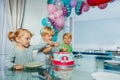 Three kids boys and girl sit at birthday party pointing to cake Royalty Free Stock Photo