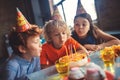 Three kids celebrating bday and blowing out candles