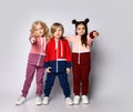 Three kids girls and boy in modern sport suits stand together pointing fingers at us. Royalty Free Stock Photo