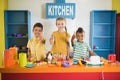 Three kids giving thumbs up at toy kitchen. Royalty Free Stock Photo