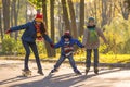 Three kids learning to ride in autumn park on rollerblades and s Royalty Free Stock Photo