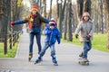 Three kids learning to ride in autumn park on rollerblades Royalty Free Stock Photo