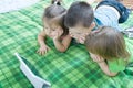 Three kids looking on tablet lying on bed at home. Children time spending. Kids using pad