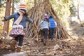 Three kids play outside shelter made of branches in a forest Royalty Free Stock Photo