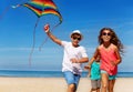 Three kids run on the beach with kite Royalty Free Stock Photo