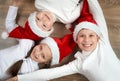 Three kids in Santa hats lying on wooden background, having fun and happy emotions, winter holiday concept Royalty Free Stock Photo