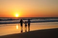 Three kids silhouettes running and jumping on beach at sunset. happy family, two school boys and one little preschool Royalty Free Stock Photo