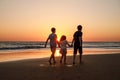 Three kids silhouettes running and jumping on beach at sunset. happy family, two school boys and one little preschool Royalty Free Stock Photo