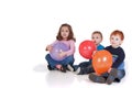 Three kids sitting with party balloons