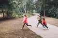 Three kids, tow girls and one boy, playing, laughing and running in a park road. Royalty Free Stock Photo