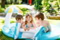 Three kids, two boys and toddler girl splash in an outdoors swimming pool in summer. Happy children, brothers and sister playing Royalty Free Stock Photo