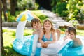 Three kids, two boys and toddler girl splash in an outdoors swimming pool in summer. Happy children, brothers and sister Royalty Free Stock Photo