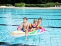 Three kids, two boys and toddler girl splash in an outdoors swimming pool in summer. Happy children, brothers and sister Royalty Free Stock Photo