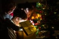 Three kids, two toddler boys and a girl, opening a golden gift b Royalty Free Stock Photo