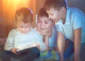 Three kids using tablet computer in a dark room Royalty Free Stock Photo