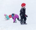 Three kids wearing helmets playing in a snowy slope