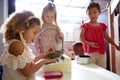 Three kindergarten schoolgirls playing shop in a playhouse at an infant school, backlit Royalty Free Stock Photo