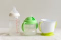 Three kinds of bottles and cups with water for baby. Royalty Free Stock Photo