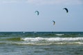 Three kiters ride on the waves of sea