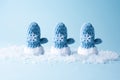 Three knitted blue mittens in the snow on a blue background