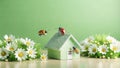 Three ladybugs surround a small green house with white flowers Royalty Free Stock Photo