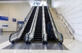 Three large escalators with a man in a business suit carrying a suitcase riding up on one of them