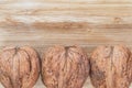 Three large inshell walnuts lie below in a line on a brown wooden surface, above is an empty place Royalty Free Stock Photo