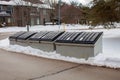 Three large metal garbage bin sits on the side of a street in a condo corporation