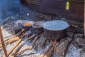 Three large saucepans resting on log fires