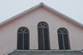 Three large windows on the pink concrete wall of the attic Royalty Free Stock Photo