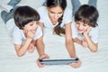 Entertainment for kids. Three latin children looking cheerful while using digital tablet, lying on the bed at home