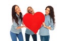 Three laughing casual women holding a big red heart