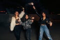 Three laughing female friends waving sparklers