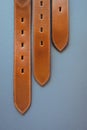 Three leather brown belts on dark background